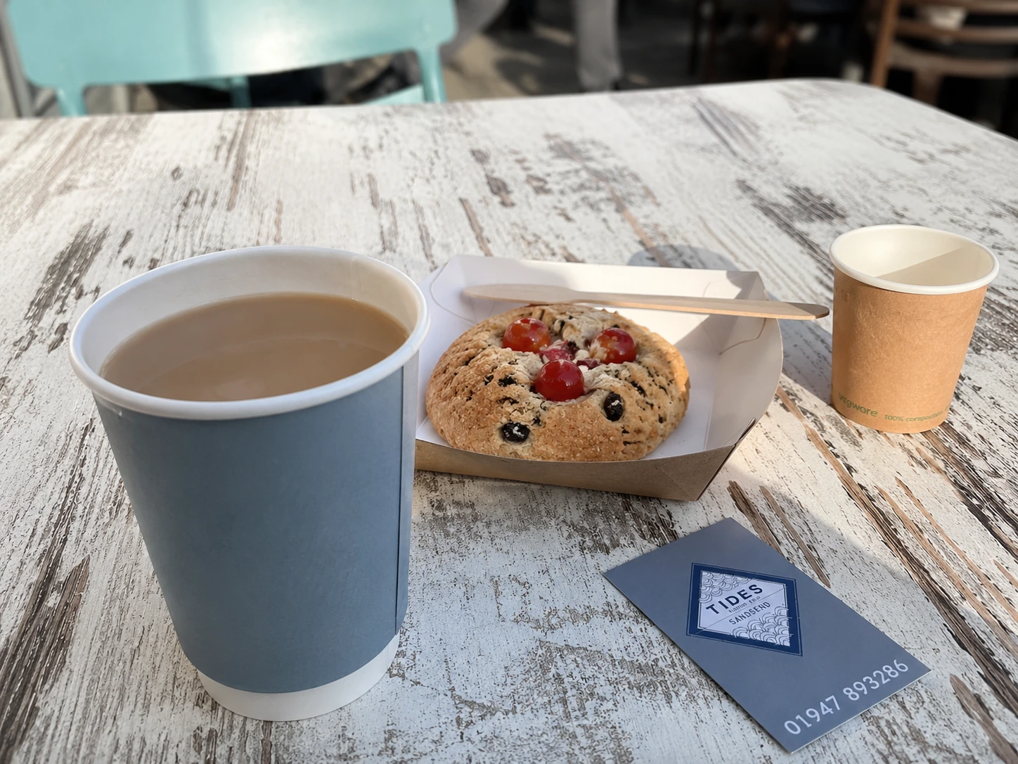 A hot drink and fruit-topped bake on an outdoor table at Tides Sandsend